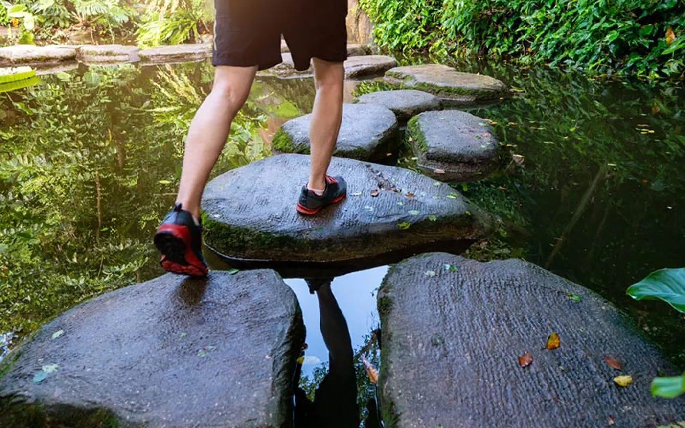 A person walking on stone steps on an outdoor pond.